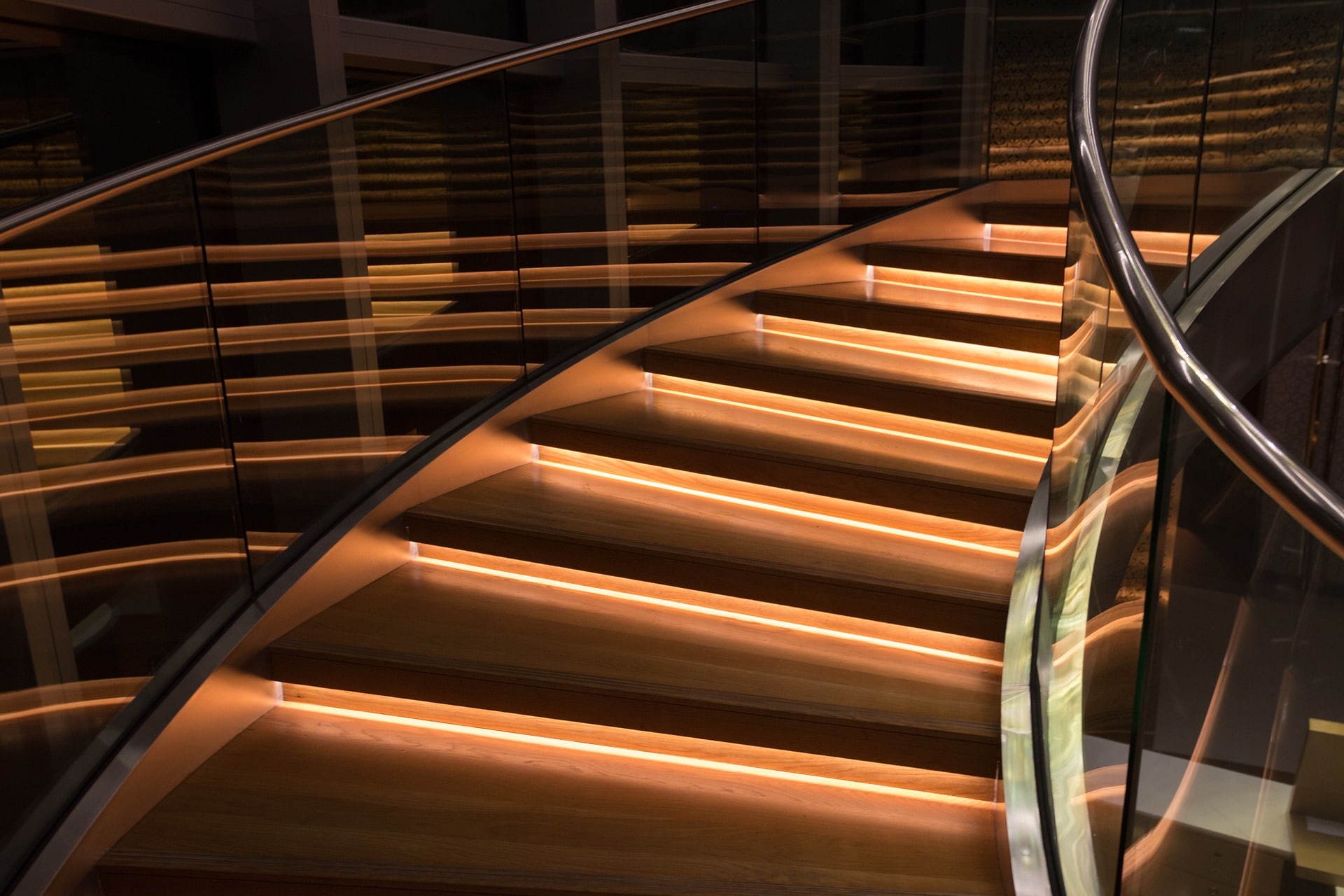 Custom wood, glass, and metal spiral staircase with LED lighting