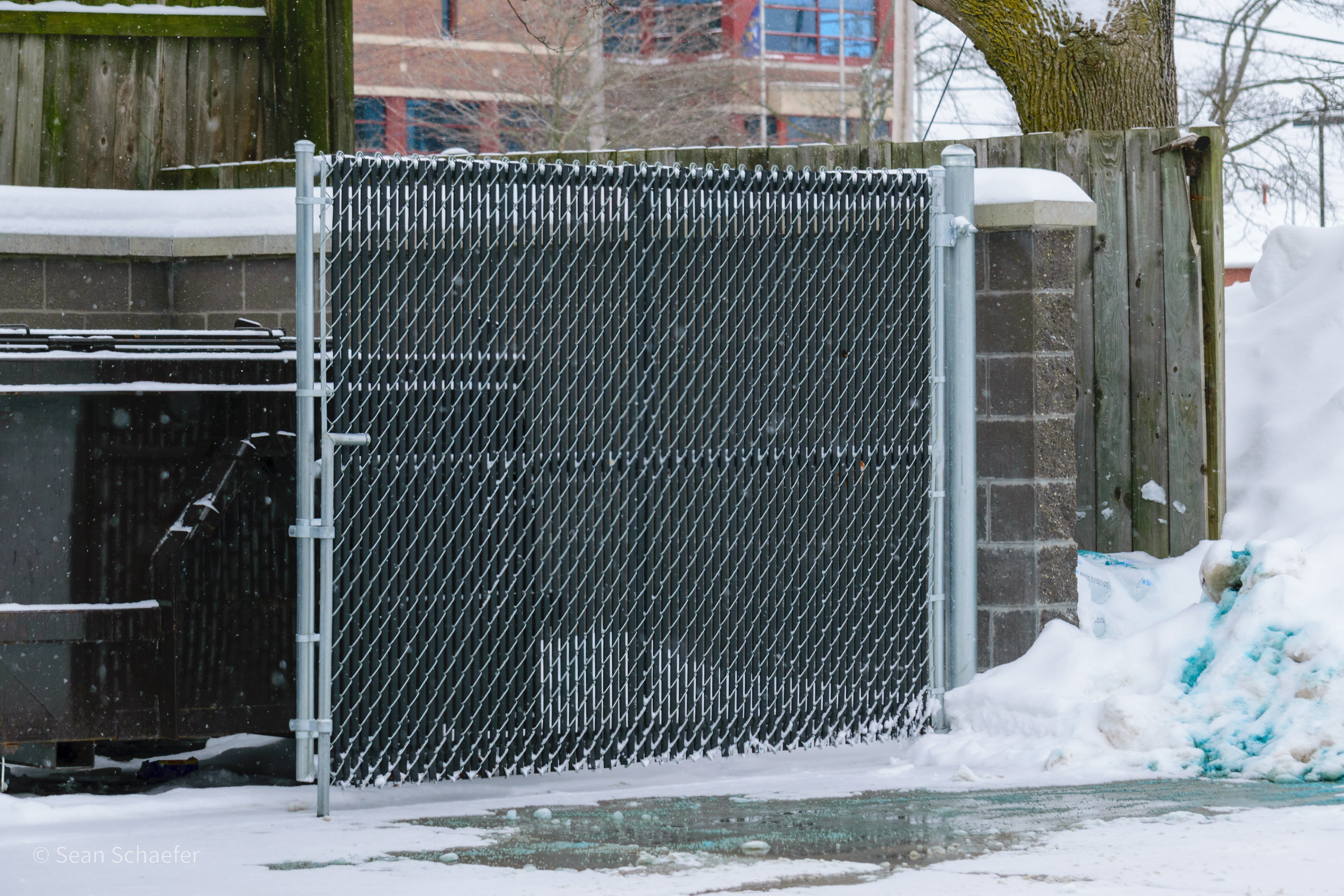 Custom galvanized steel chain link double-swing dumpster gates with locking PVC slats at Metro Place Apartments